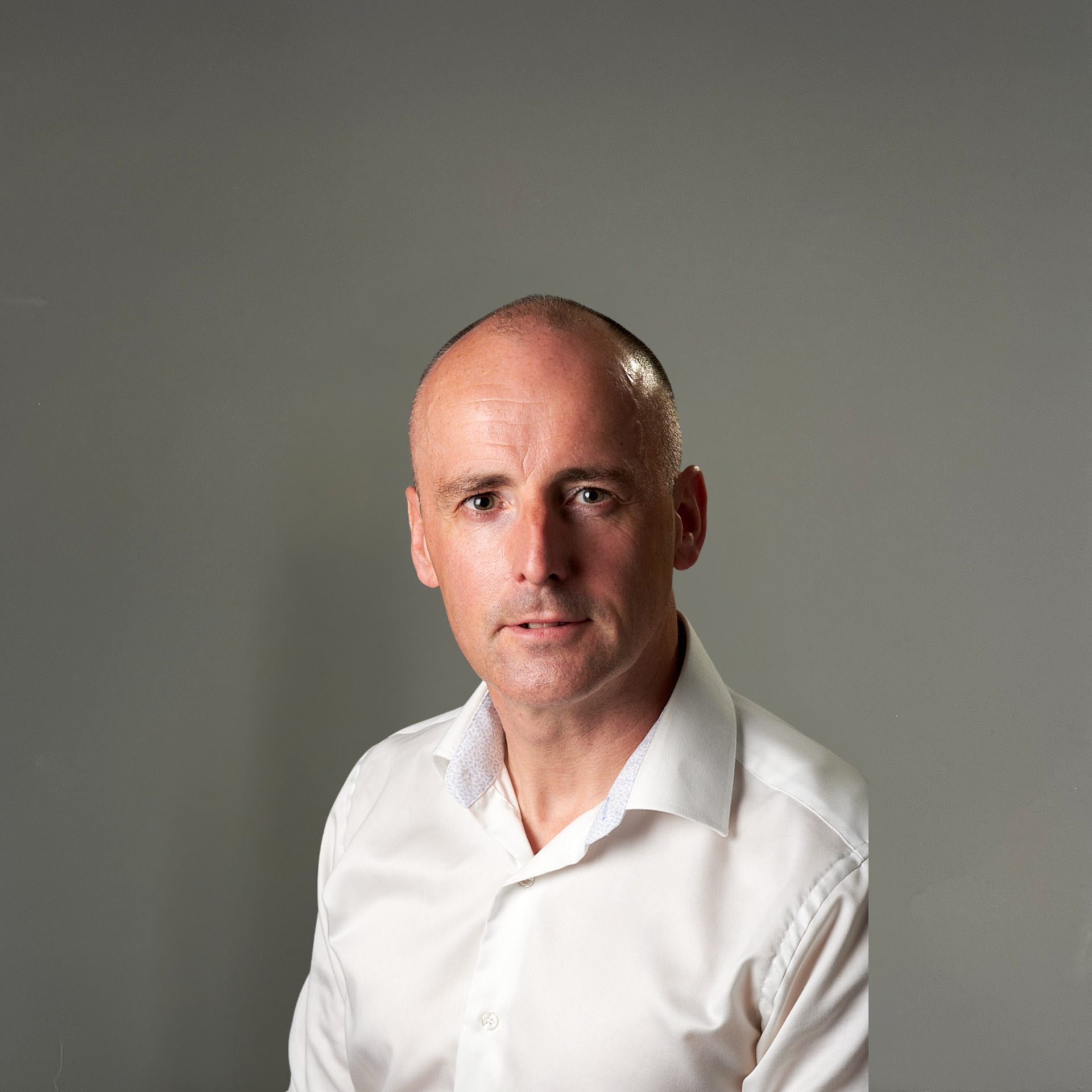A bald man in a suit and blue shirt is smiling for the camera.