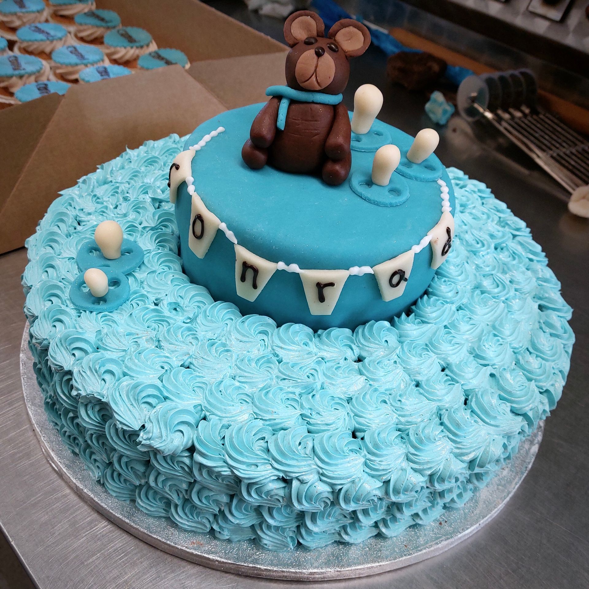 en baby shower kage med blå frosting og en bamse på toppen