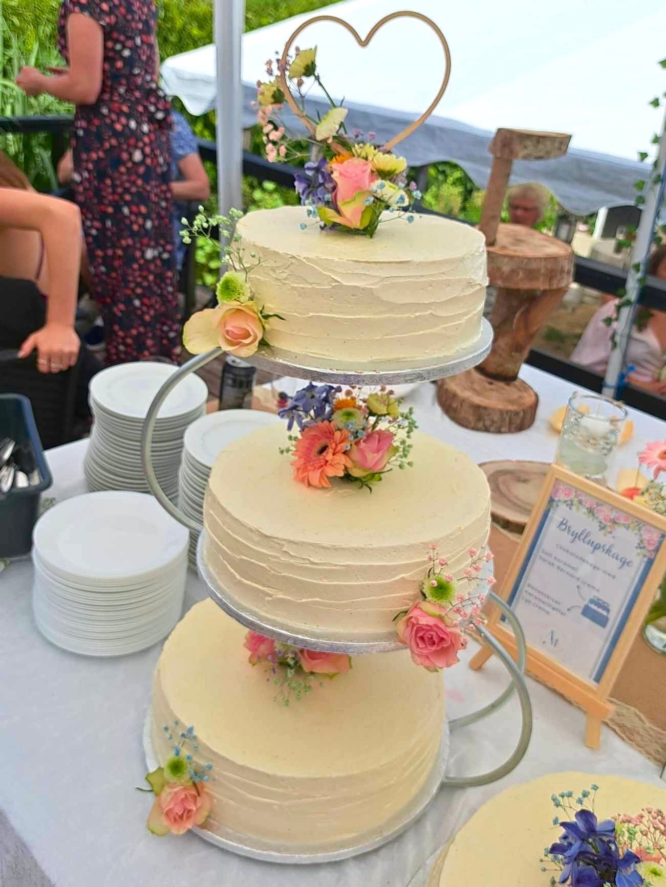 tre kager er stablet oven på hinanden på et bord med et skilt, der siger 'trouwtaartje' på det