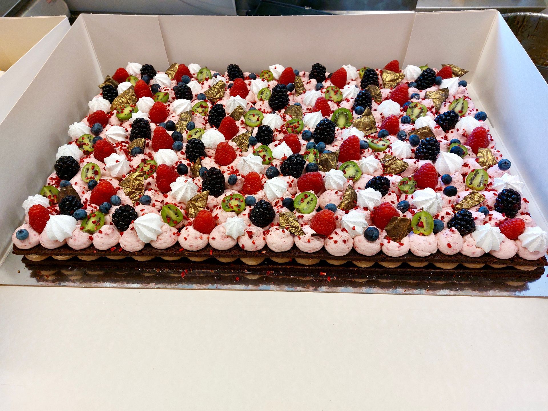 en kage med bær og flødeskum i en æske