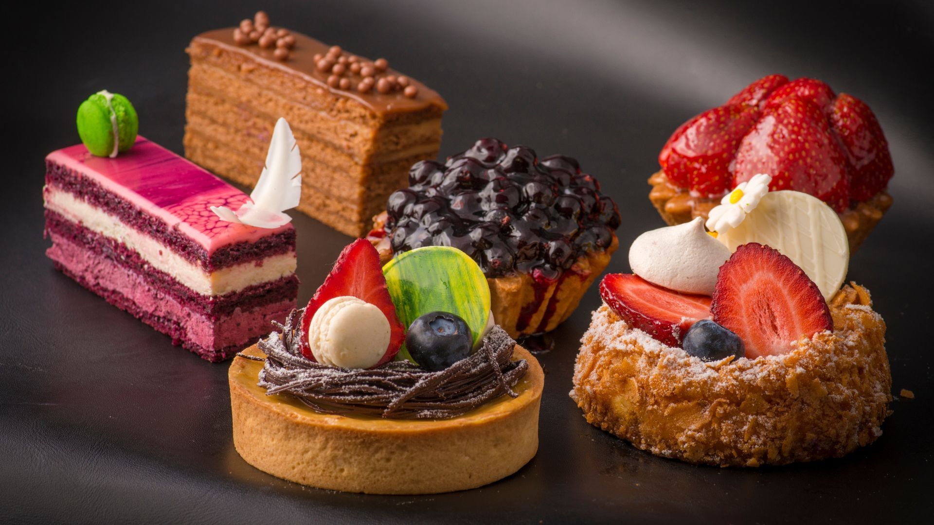 en række desserter er på en sort overflade