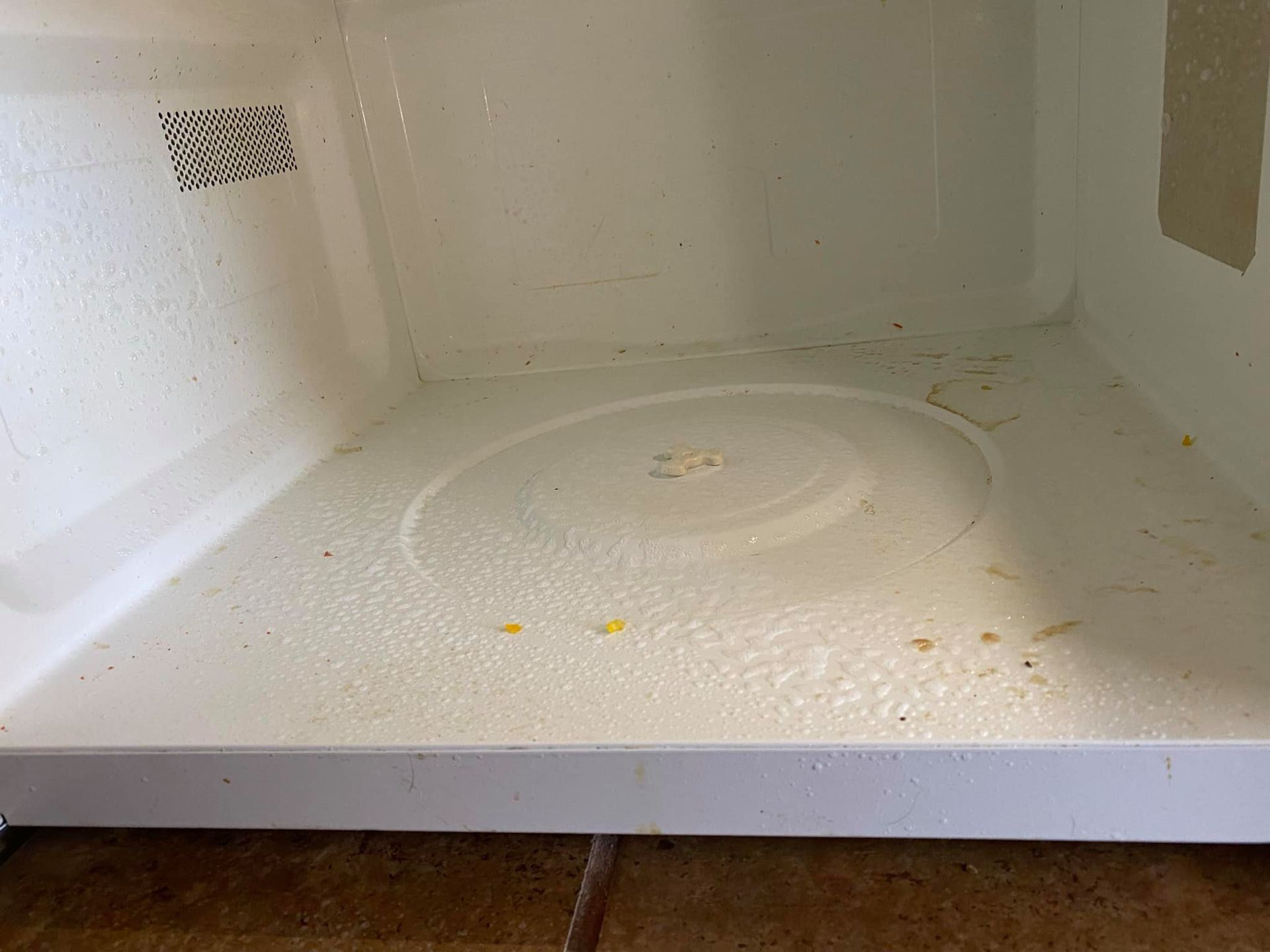 Empty white microwave interior with a few crumbs and stains