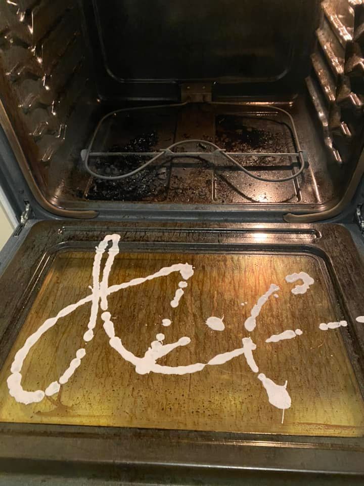 Open oven with a white sauce spelling “Hey” on the bottom tray.