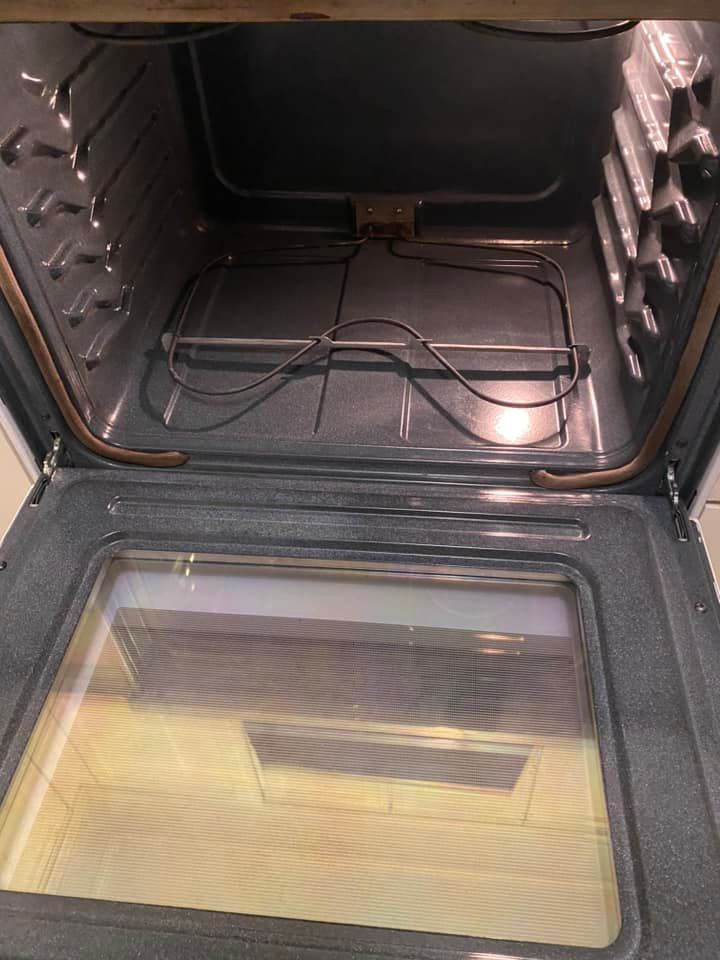 Open oven with empty racks and a glass door reflecting the kitchen lights