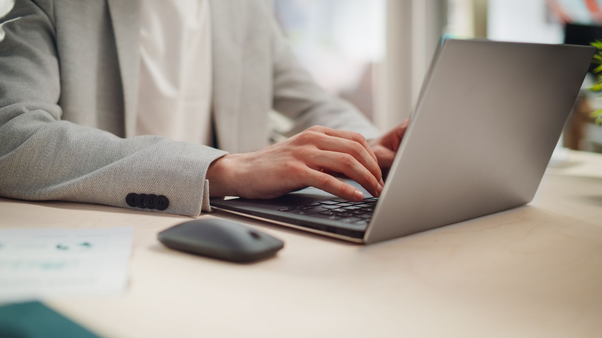 A person is typing on a laptop computer at a desk.