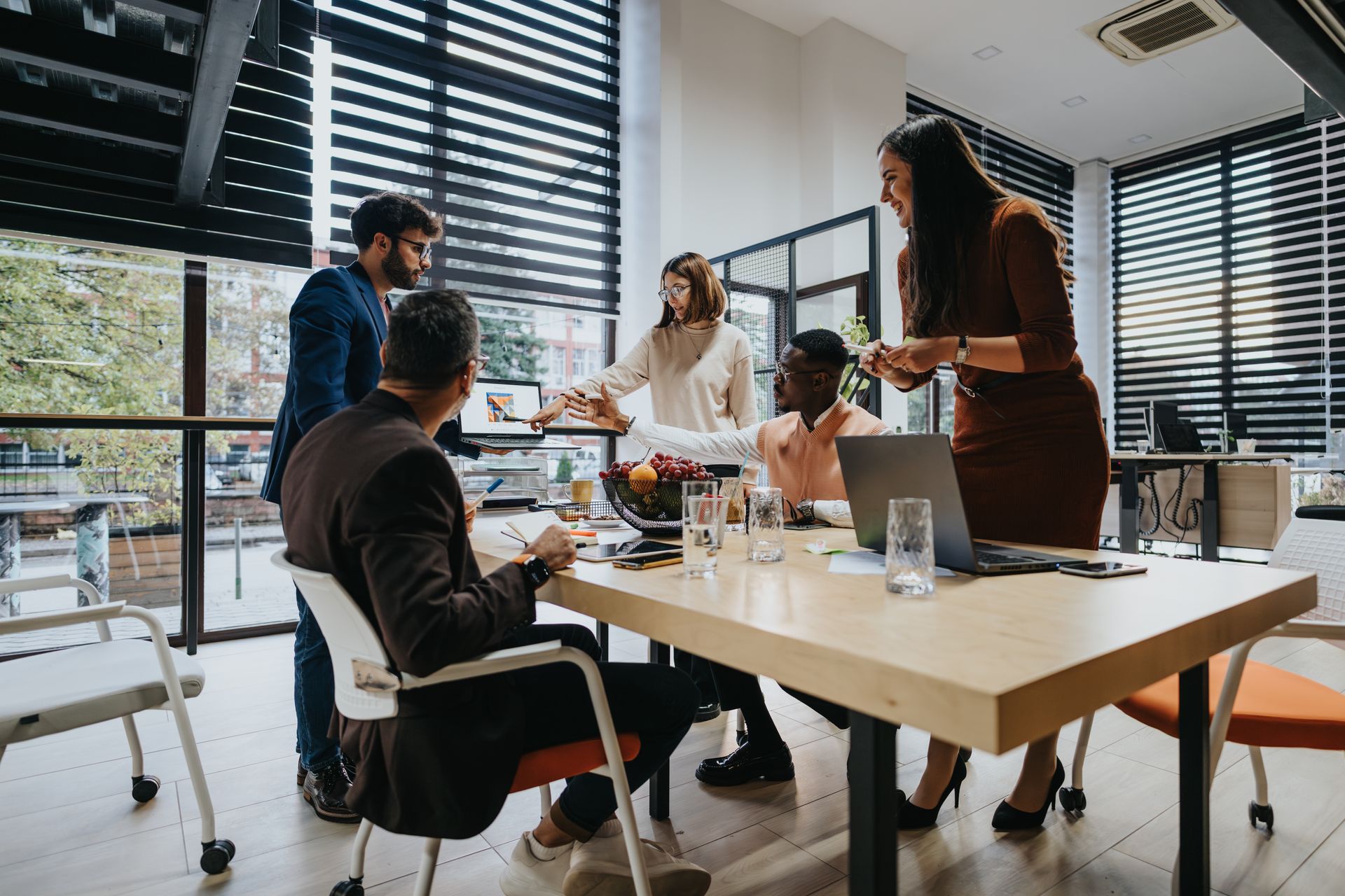 A group of people are sitting around a table in an office having a meeting.