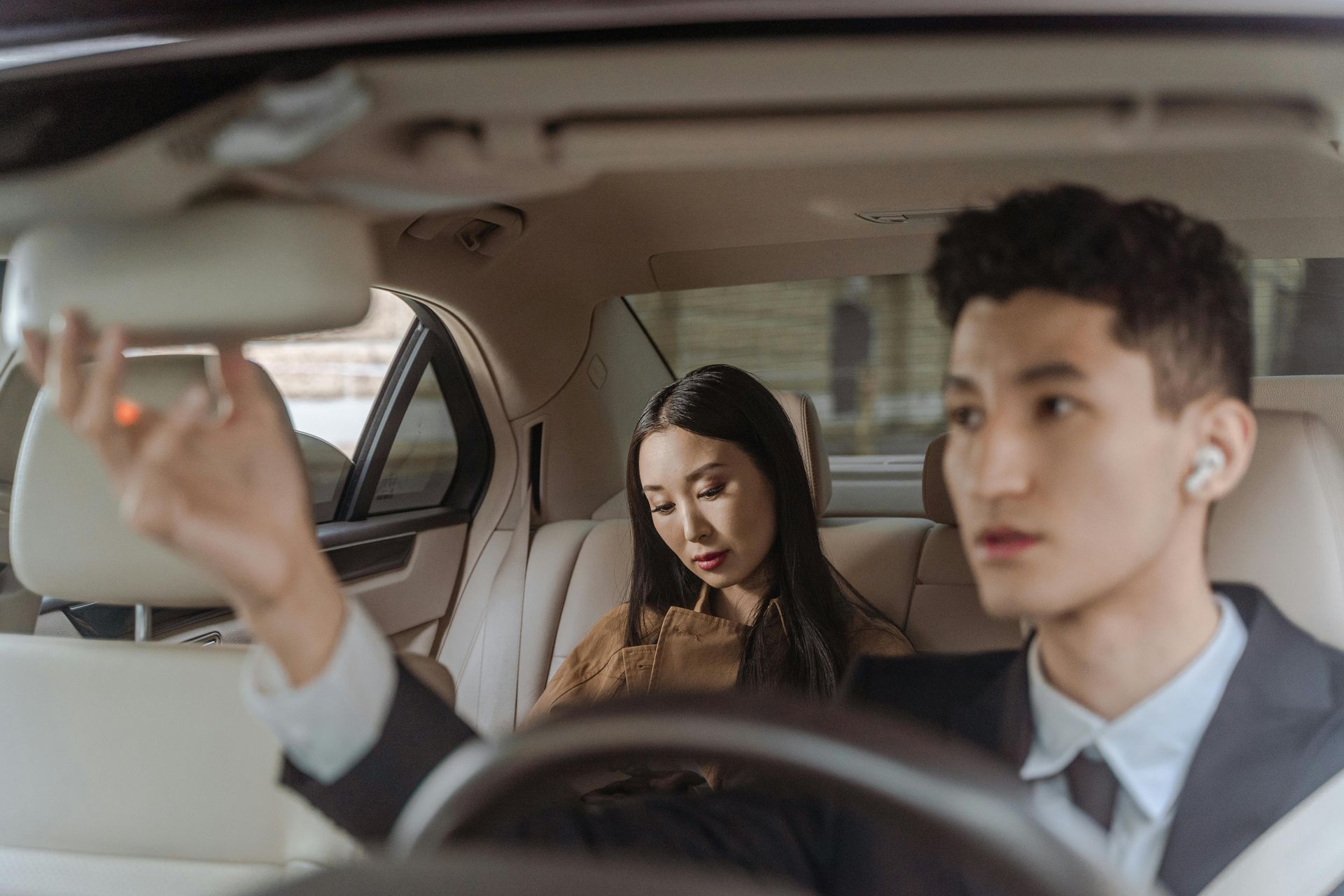 A man is driving a car with a woman sitting in the back seat.