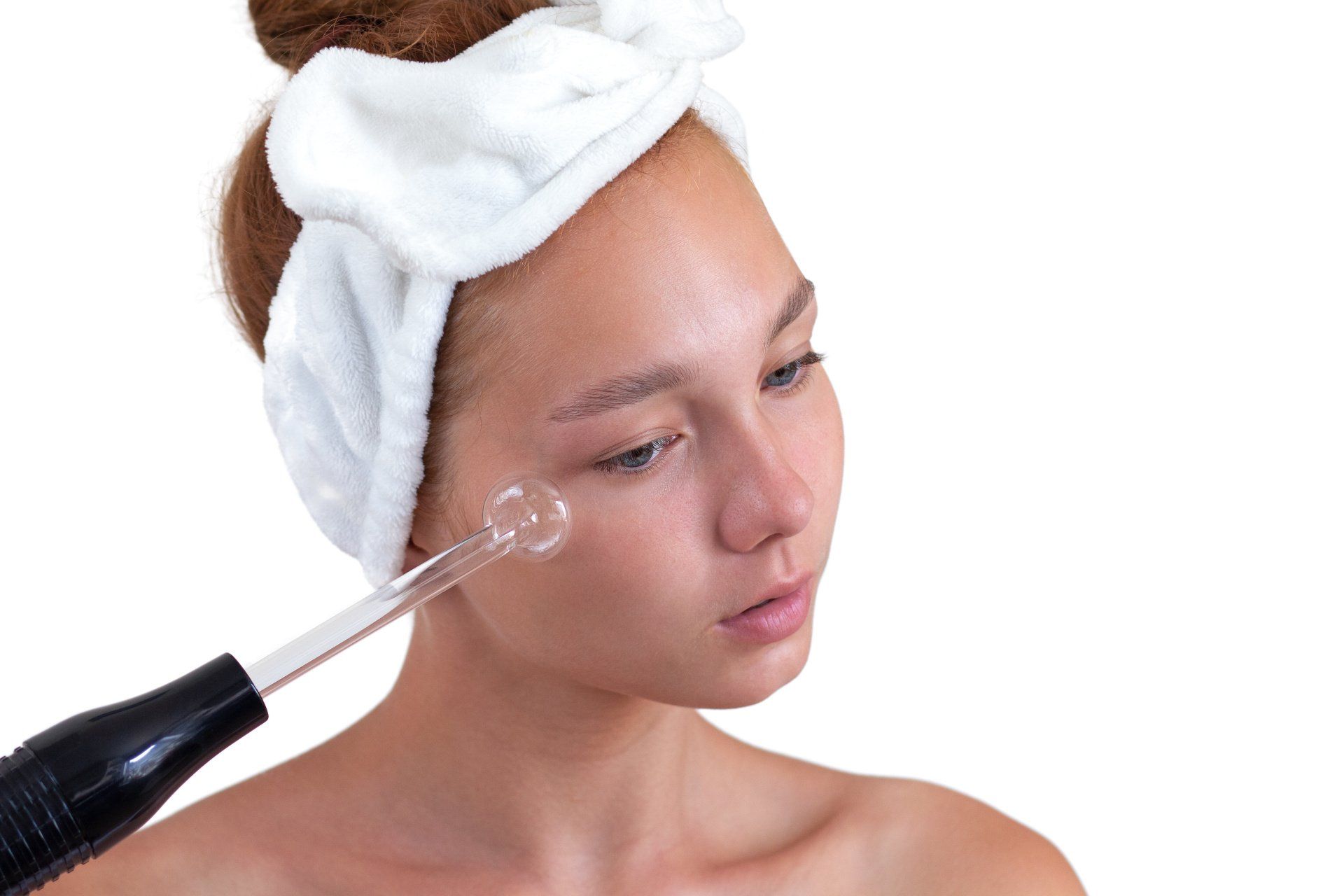 Eine Frau mit einem Handtuch auf dem Kopf bekommt eine Gesichtsbehandlung.