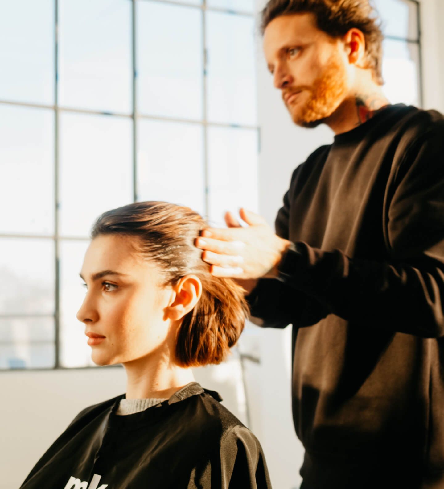 Donna con lunghi capelli ondulati, con un top nero testurizzato, che guarda direttamente l'osservatore. Bianco e nero.