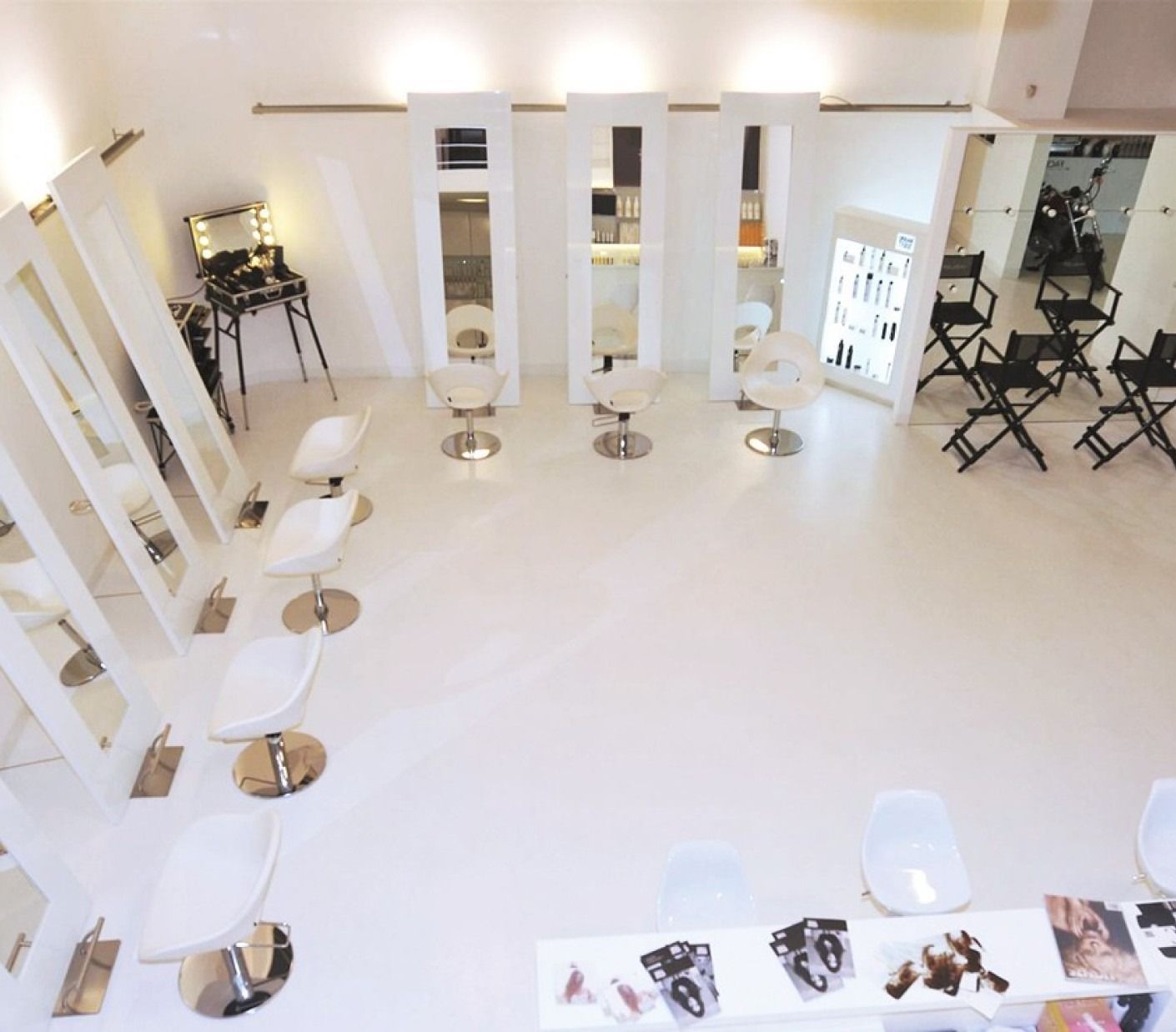 Elegante salone da parrucchiere con pareti scure, pavimento in marmo e sedie marroni.