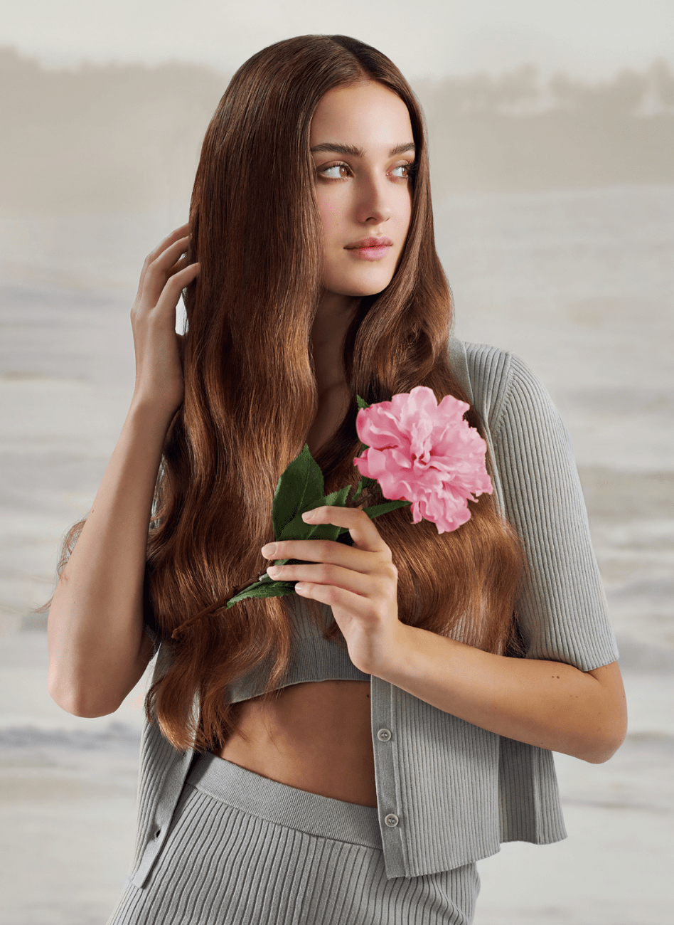 Donna con abito grigio e lunghi capelli neri che svolazzano nel vento.