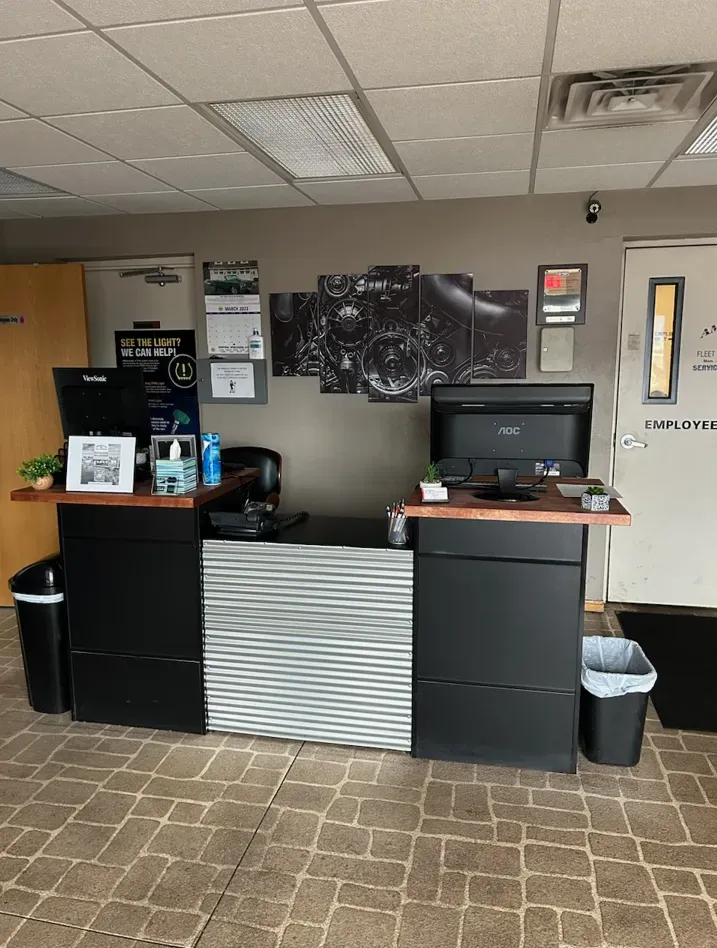 Reception desk in an office with a black and silver design. Computers, art, and trash cans present. | American Fleet & Auto Service