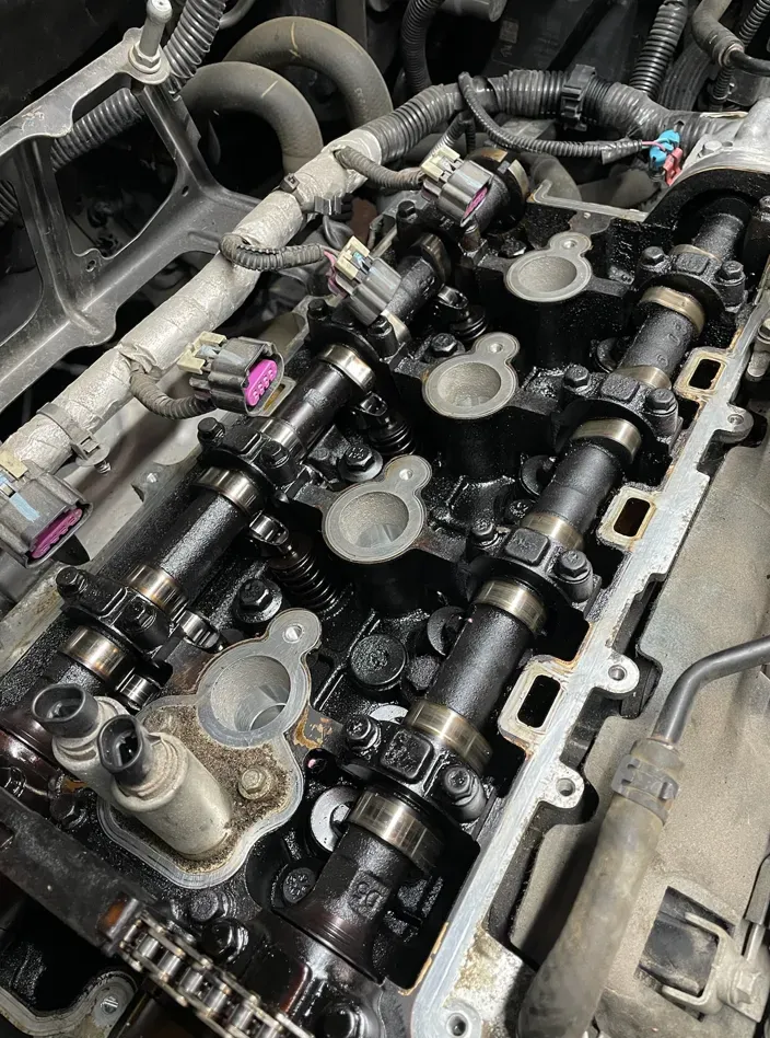 Engine components: camshafts, chains, and valve train with visible oil. | American Fleet & Auto Service | American Fleet & Auto Service