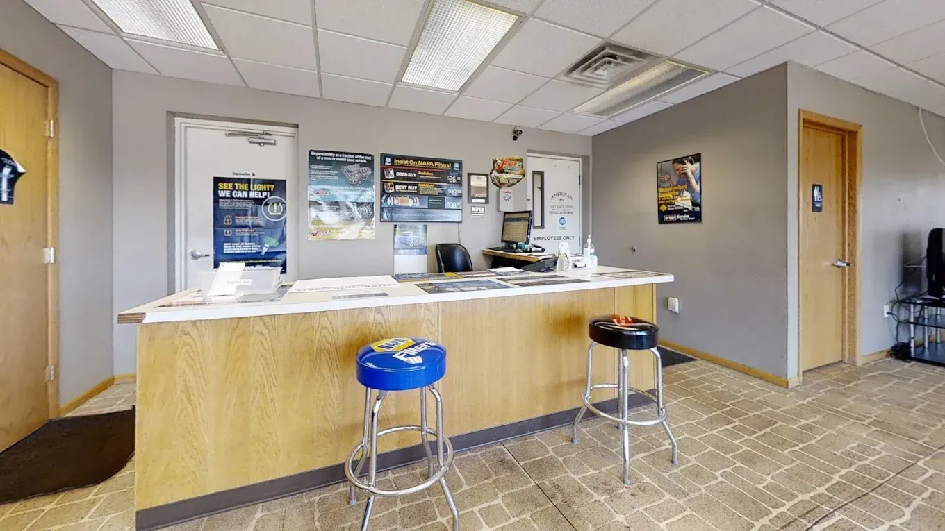 Reception area of a business with desk, stools, posters, and doors. Neutral colors with blue stool and carpet. | American Fleet & Auto Service
