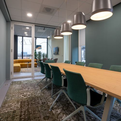 A conference room with a long wooden table and green chairs