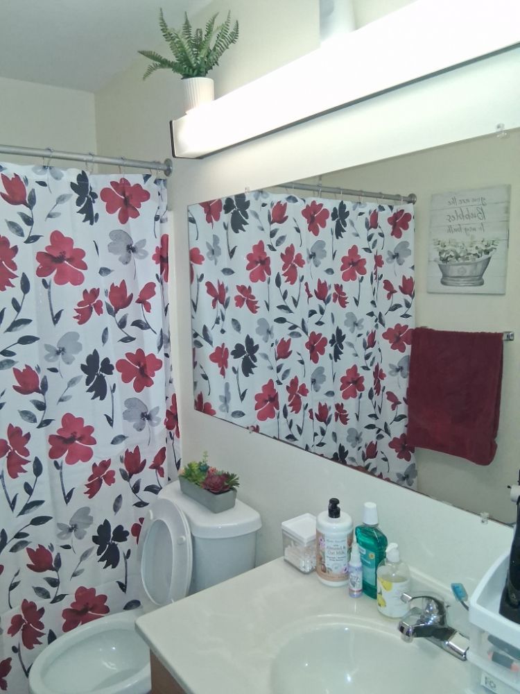 A bathroom with a floral shower curtain and a sink