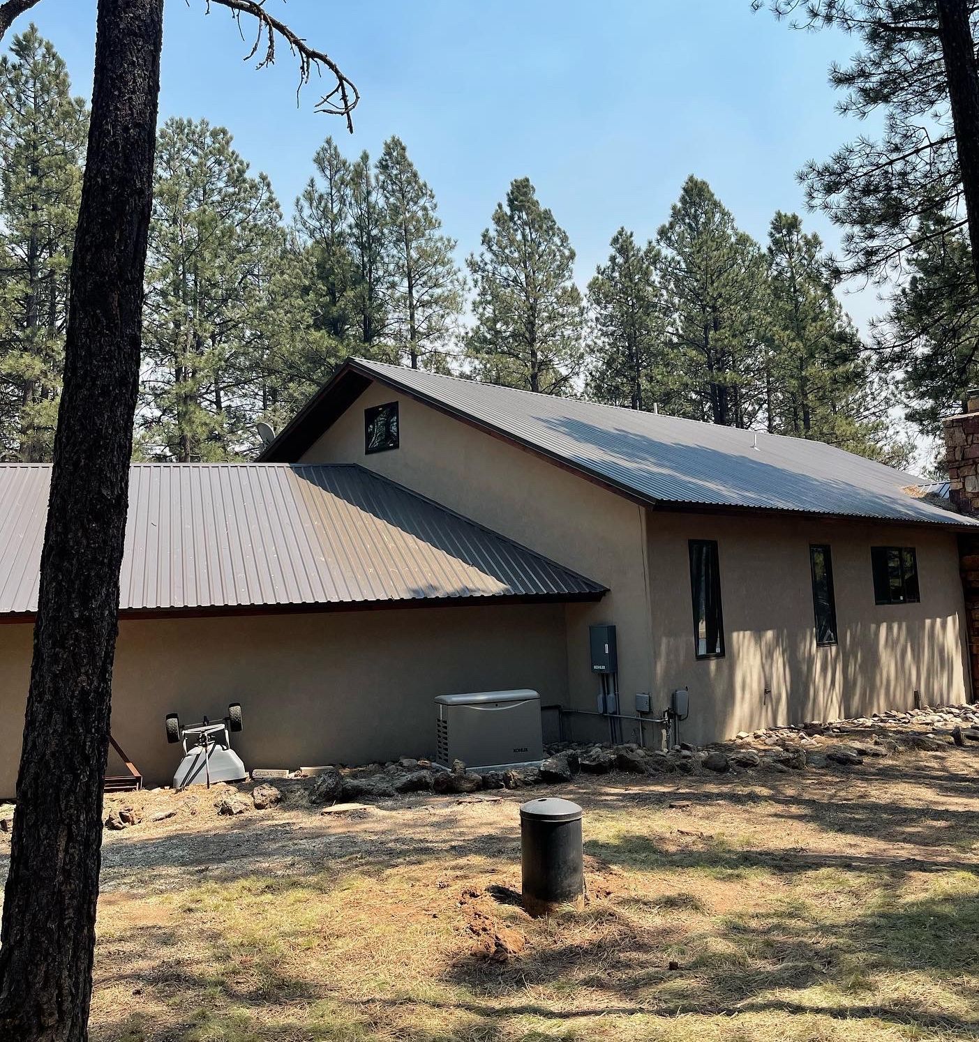 After Taos Tree removed several trees from in front of a large territorial style stucco home in a forested area.