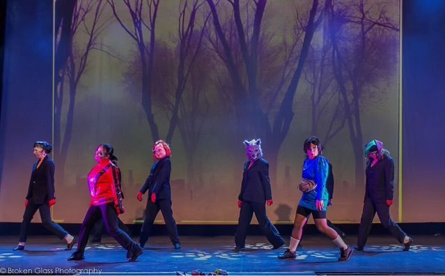 A group of people are walking on a stage in front of a forest.