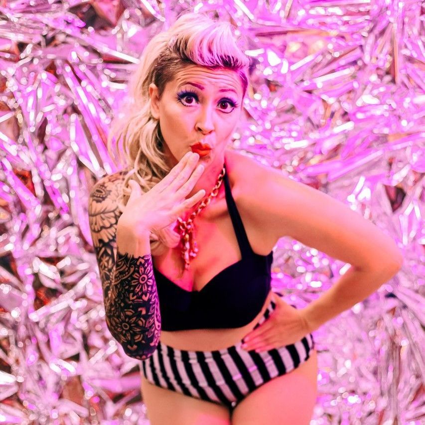 A woman in a black top and striped bottoms is covering her mouth with her hand.