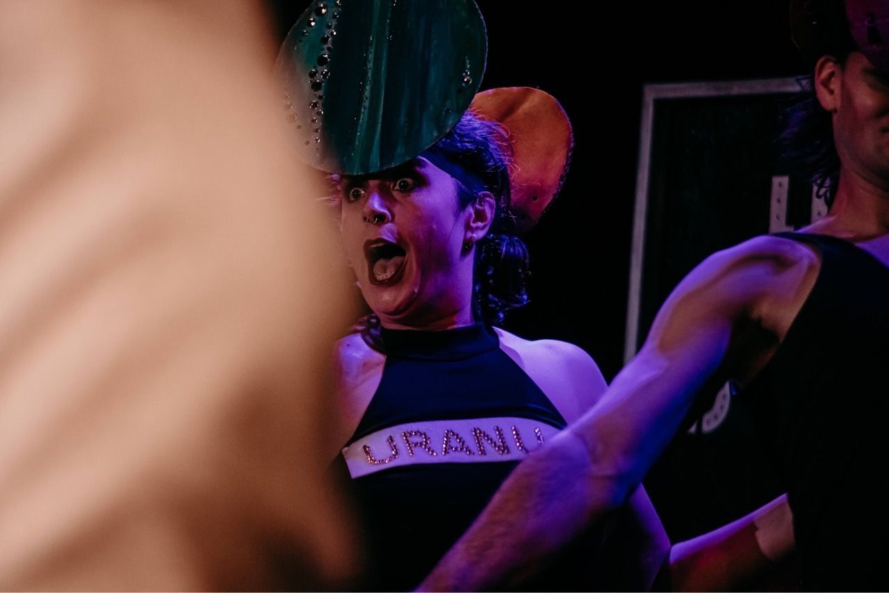 A group of people are dancing on a stage in a dark room.