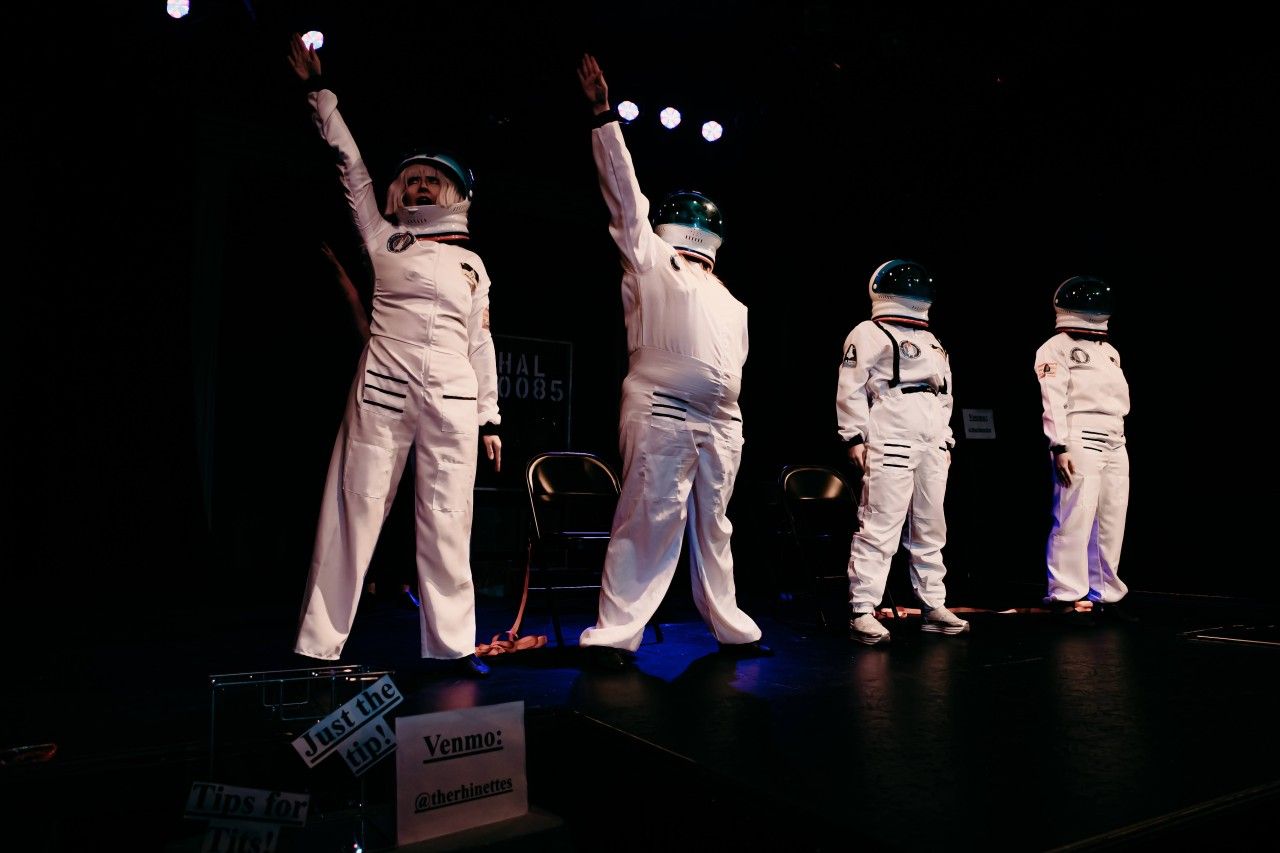 A group of astronauts are standing on a stage with their arms in the air.
