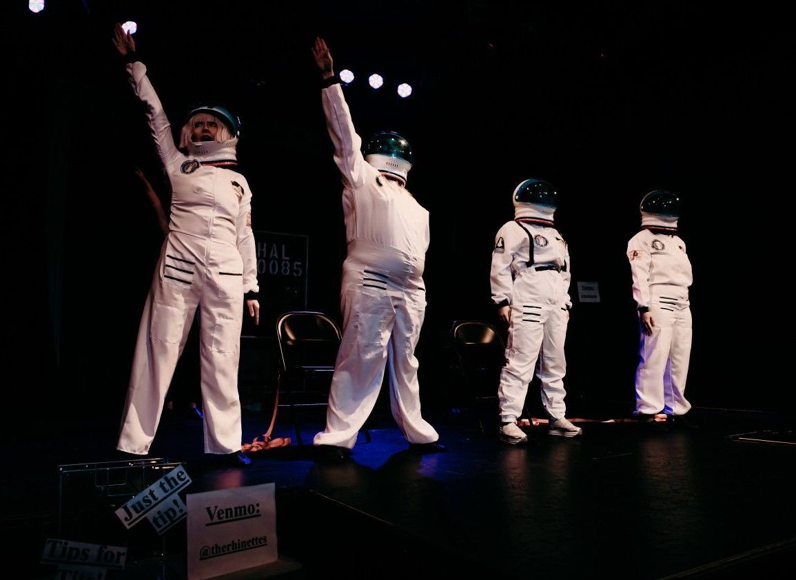 A group of astronauts are standing on a stage with their arms in the air