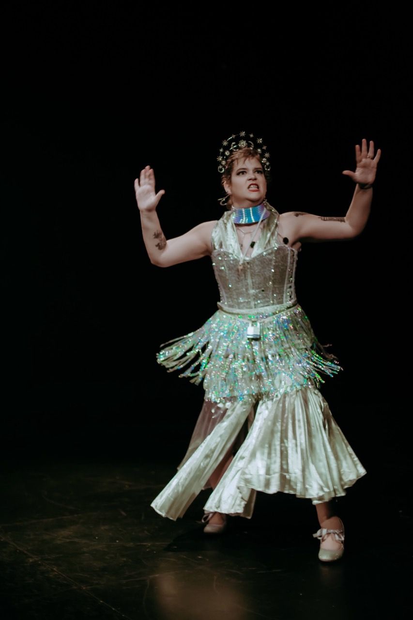 A woman in a white dress is dancing on a stage.