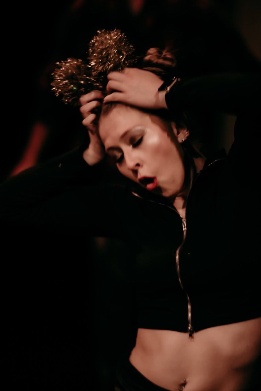 A woman in a black crop top is holding a flower in her hair.