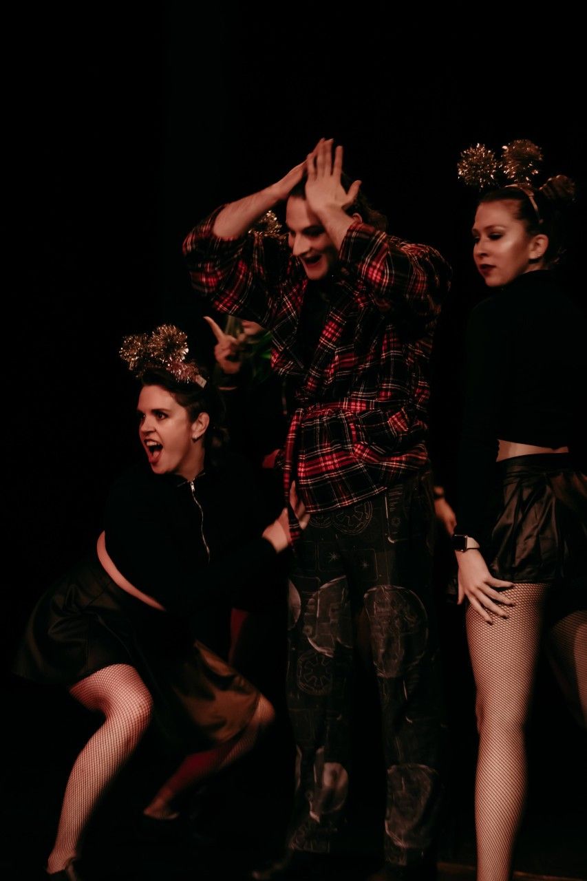 A man and two women are standing next to each other in a dark room.