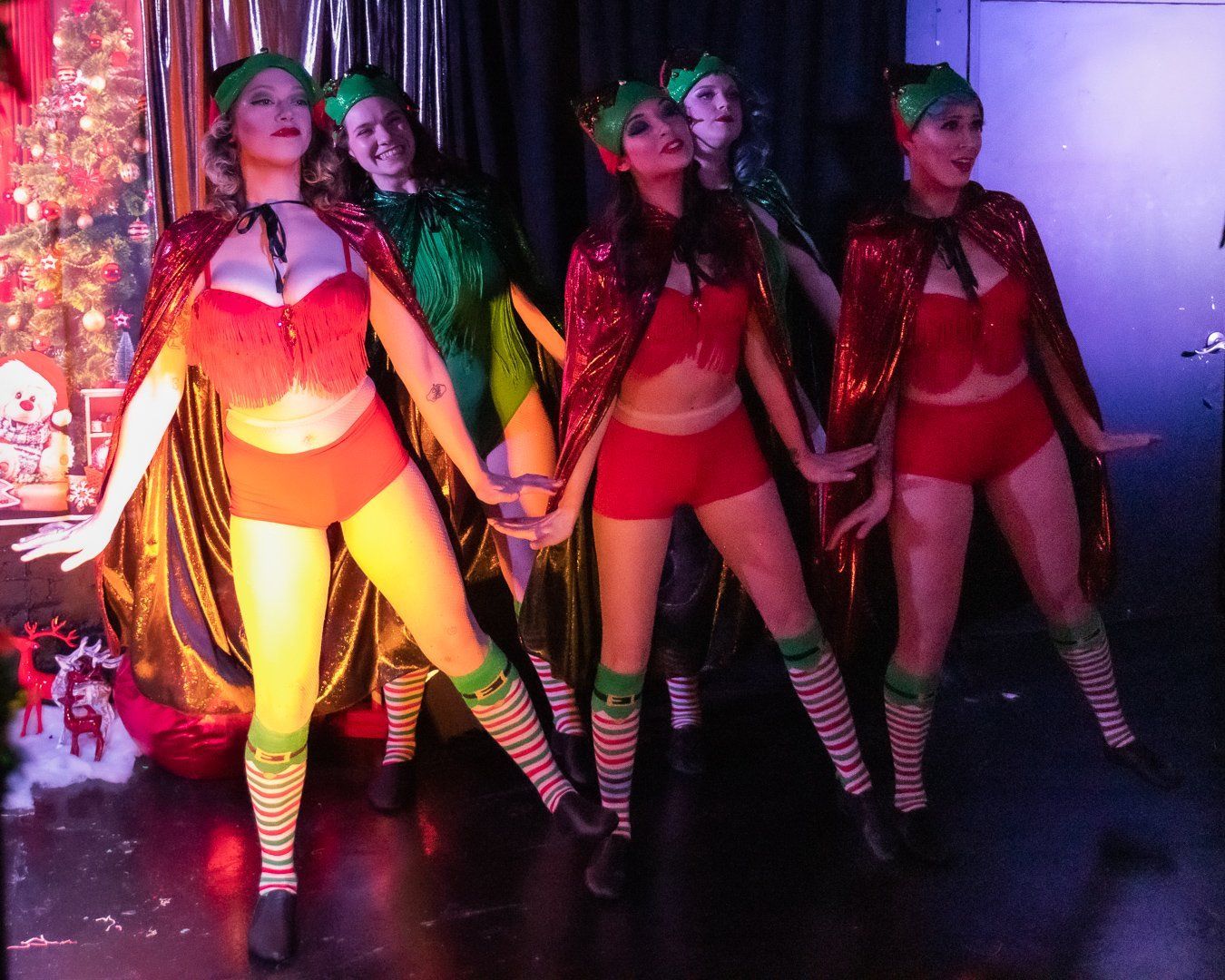 A group of women dressed as elves are dancing together