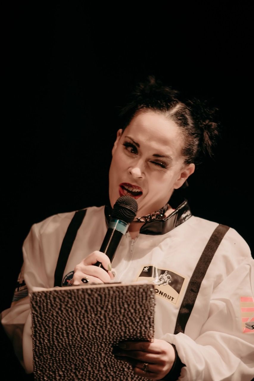 A woman is holding a microphone and a book in her hands.