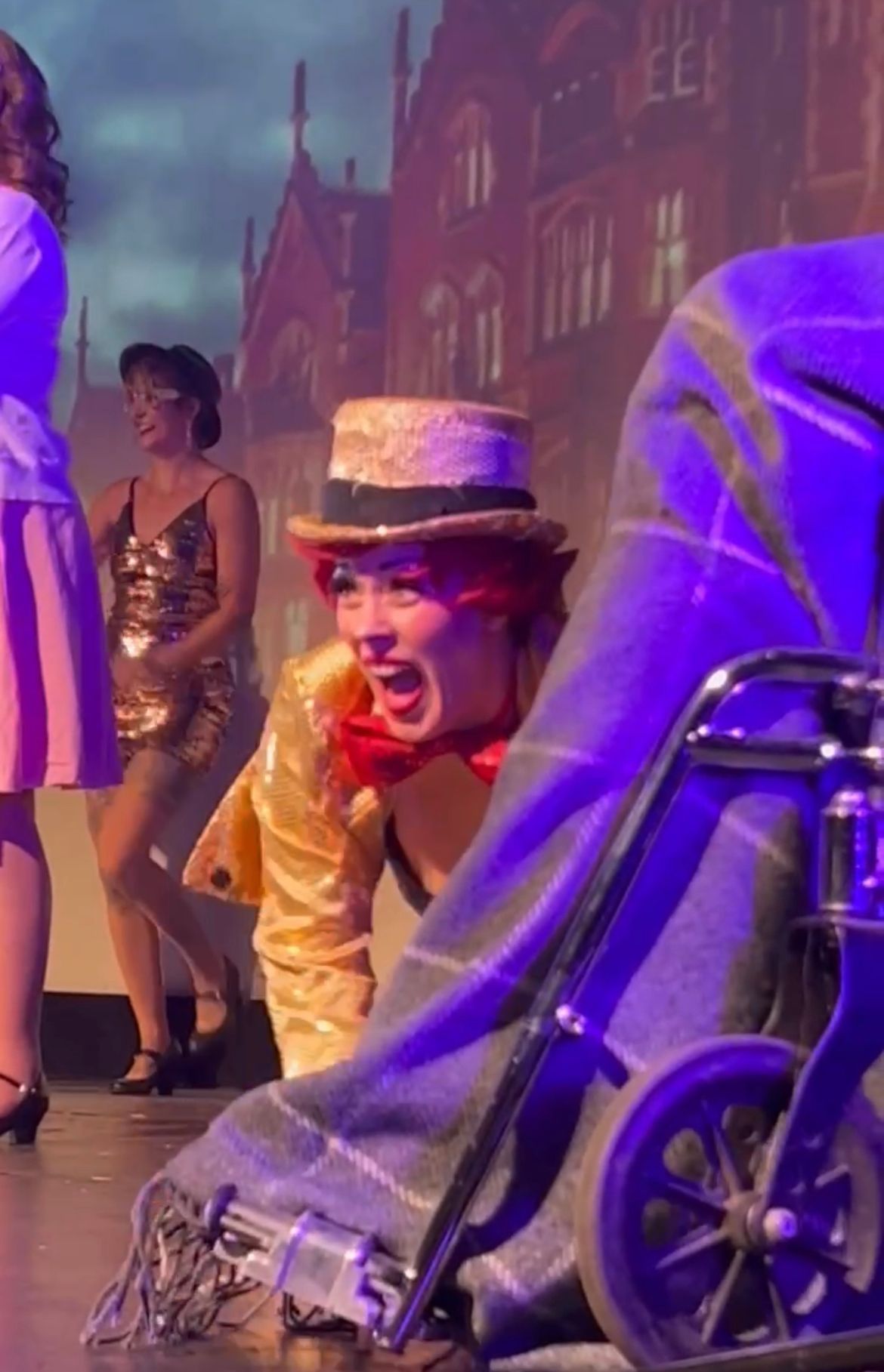A woman in a hat is sitting in a wheelchair on a stage.