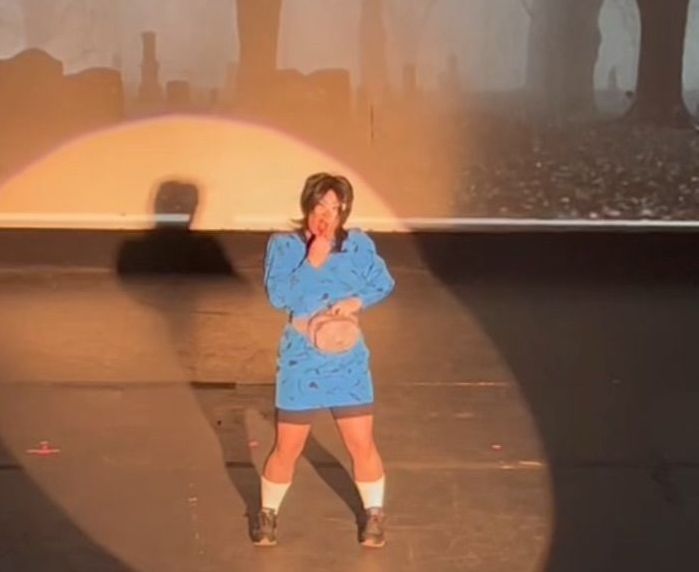 A woman in a blue dress is standing on a stage