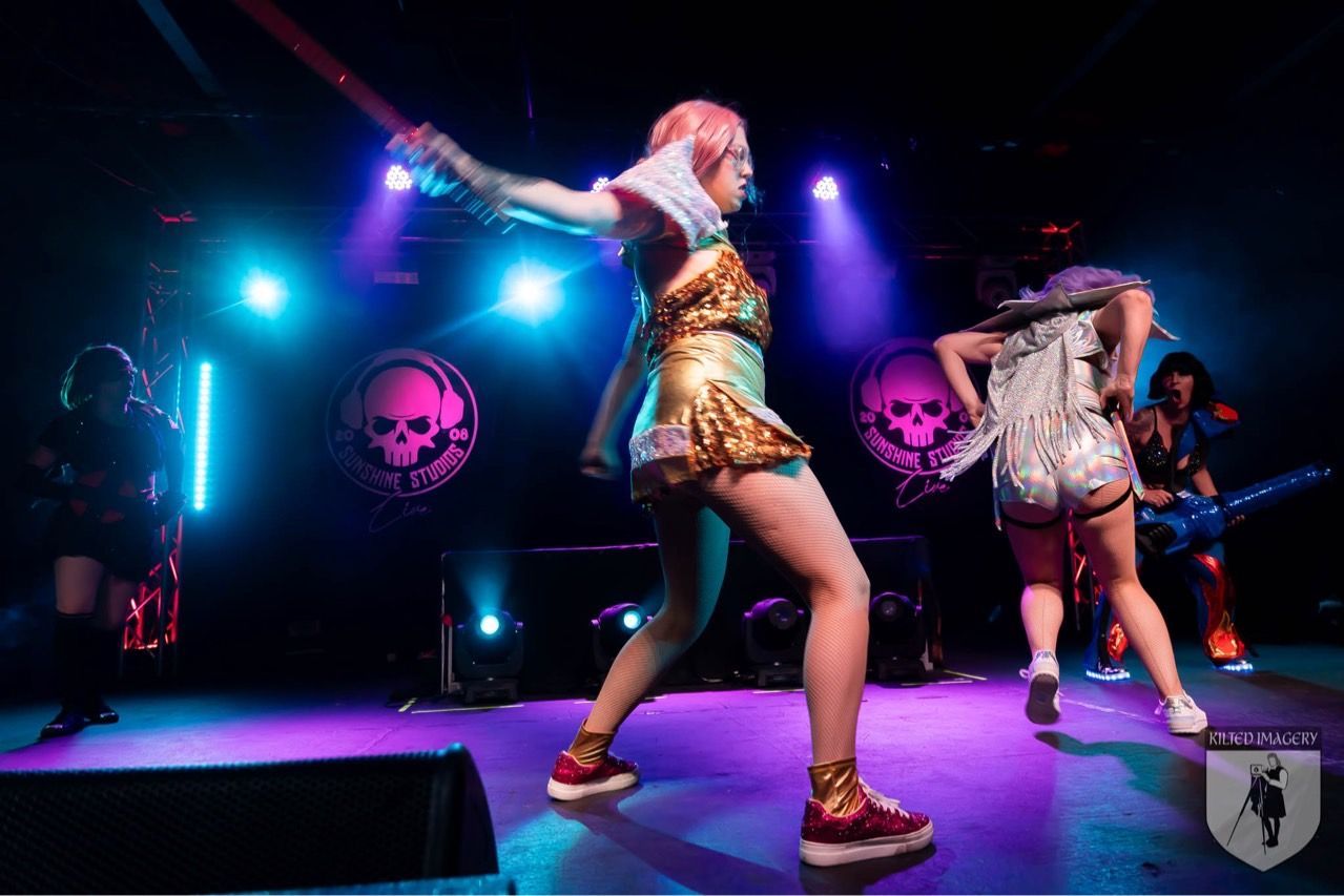 A group of women are dancing on a stage in a dark room.