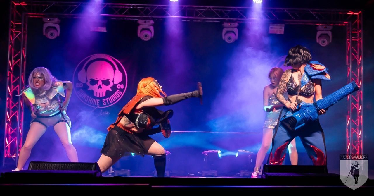 A group of people are standing on a stage in front of a purple light.