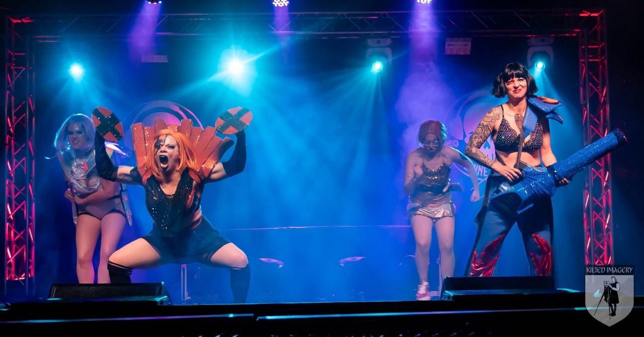 A group of women are standing on a stage in front of a blue light.