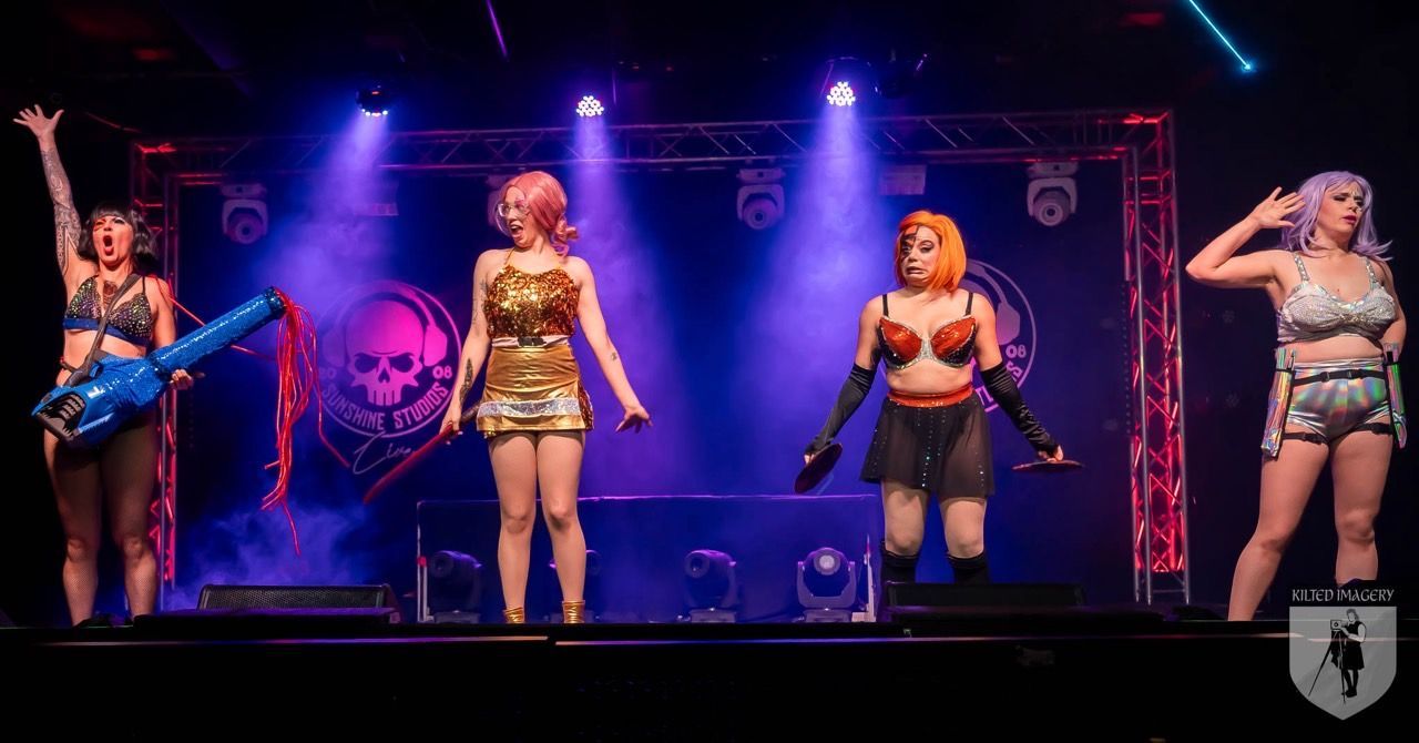A group of women are standing on a stage with purple lights.
