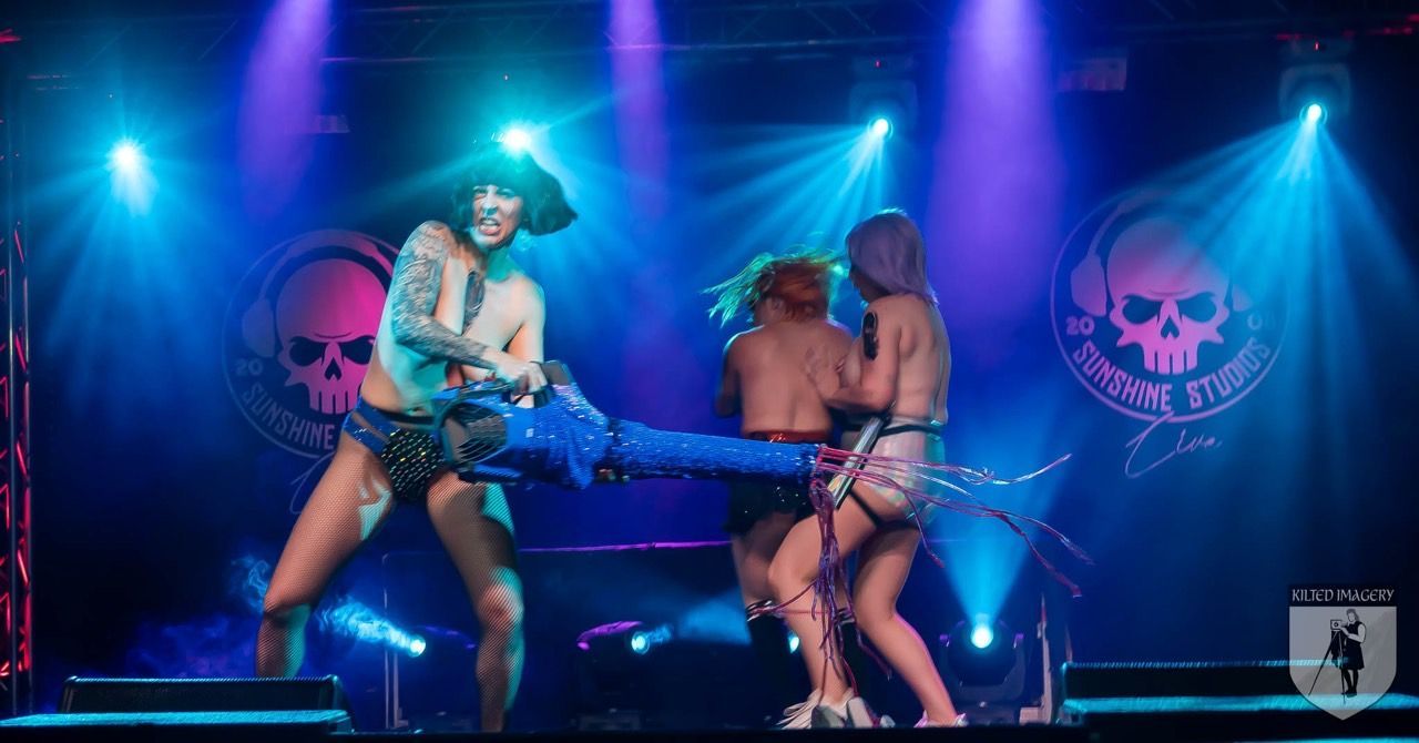 A group of people are dancing on a stage with skulls in the background.