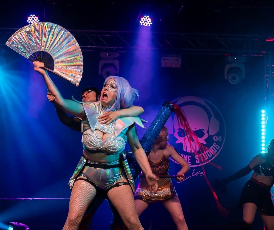 A group of women are posing for a picture in front of a curtain.