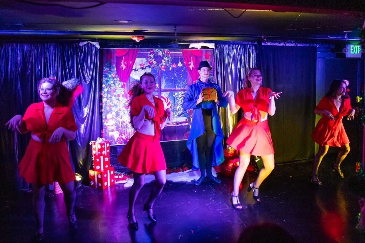 A group of people are dancing on a stage in a dark room.