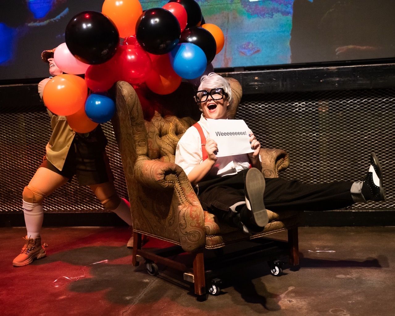 A man is sitting in a chair with balloons around him