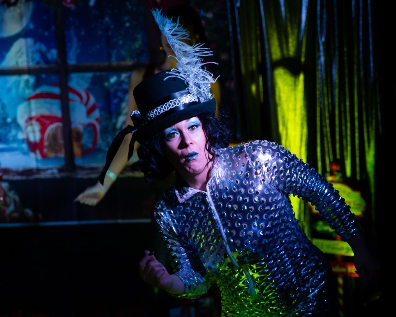 A woman in a top hat and sequined outfit is dancing on a stage.
