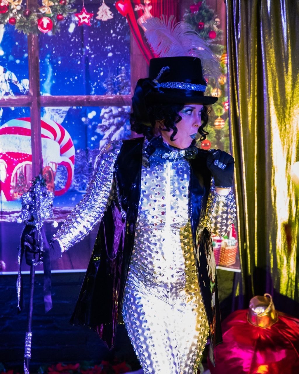 A woman in a costume is standing in front of a christmas tree.