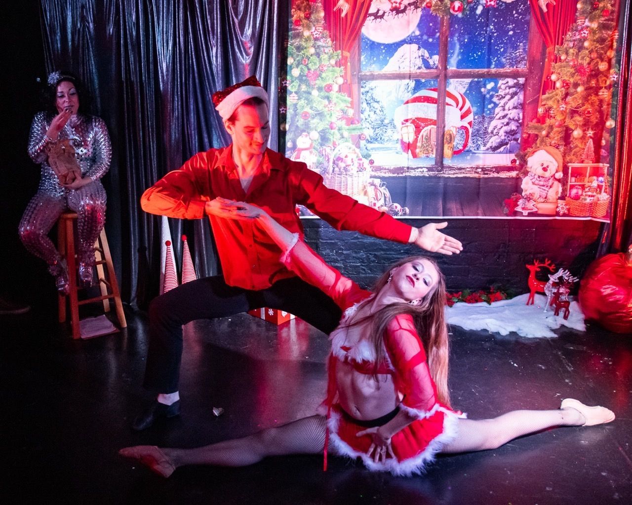 A man and a woman are dancing on a stage in front of a christmas scene.
