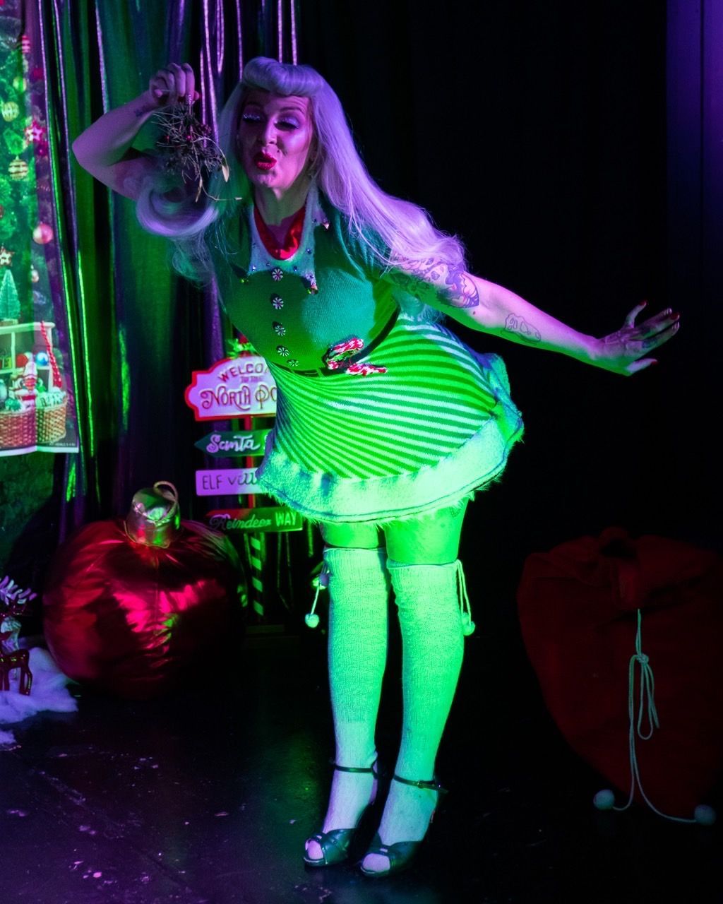 A woman in a green dress is dancing in a dark room.