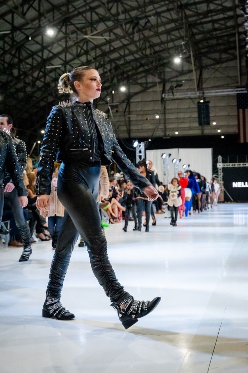 A woman is walking down a runway at a fashion show.