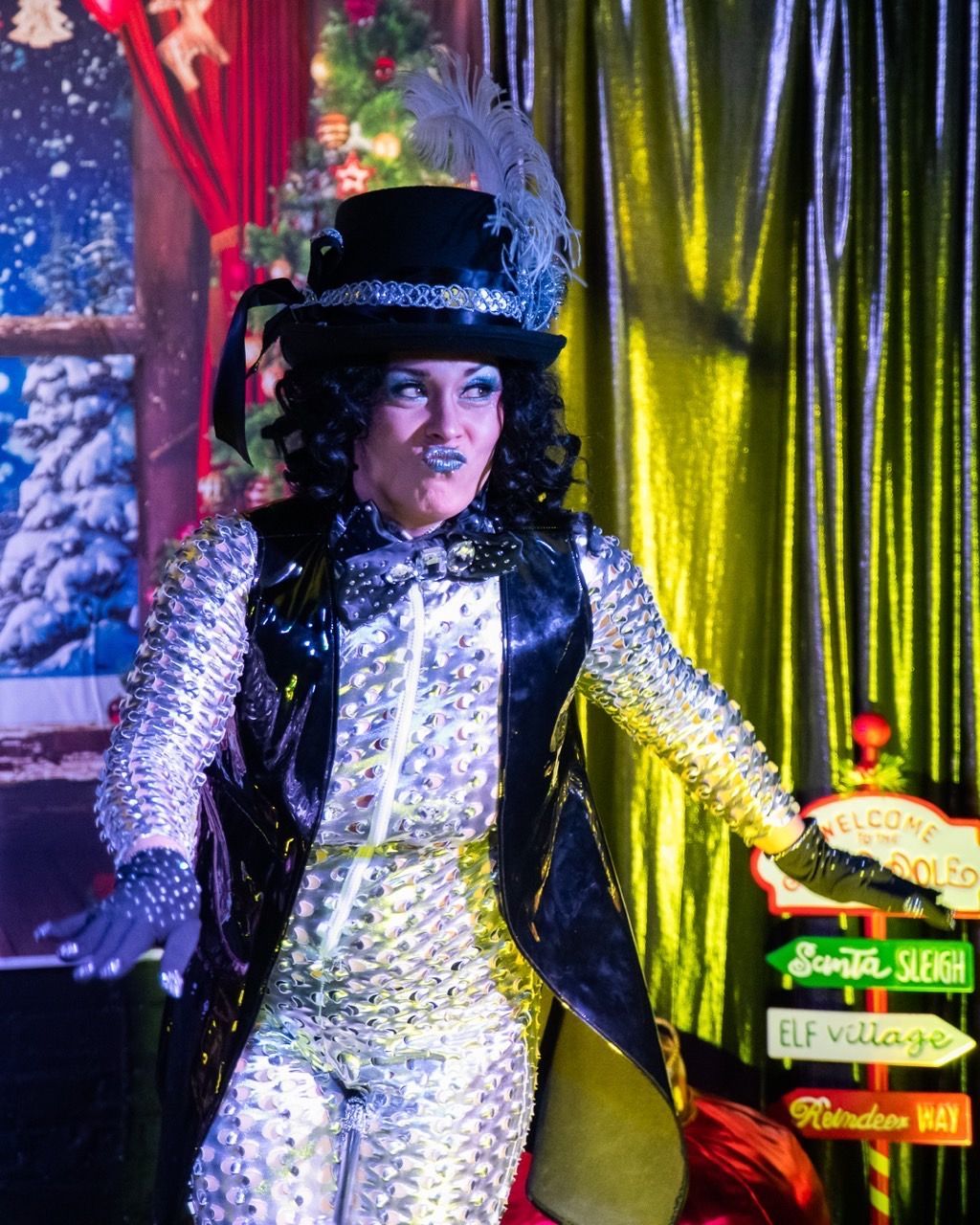 A woman in a costume is standing in front of a sign that says elf village