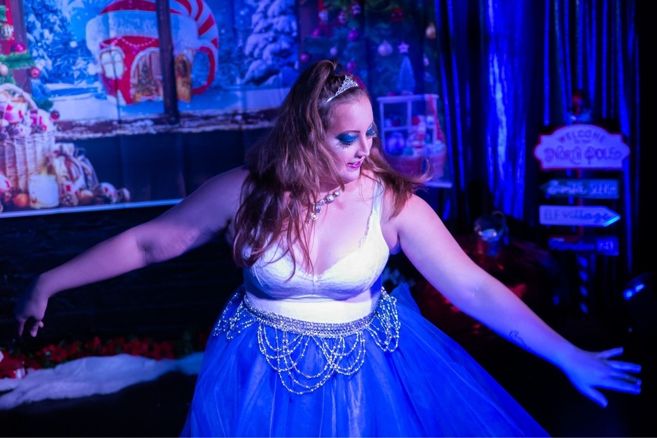 A woman in a blue dress is dancing in a dark room.