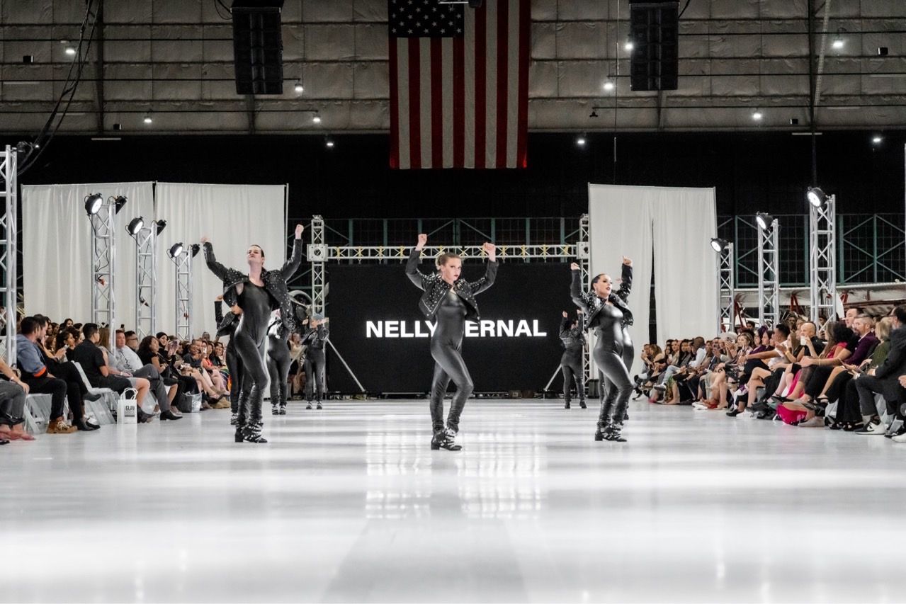 A group of people are dancing on a stage at a fashion show.