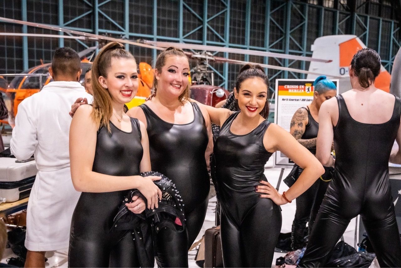 Three women in black leather jumpsuits are posing for a picture.